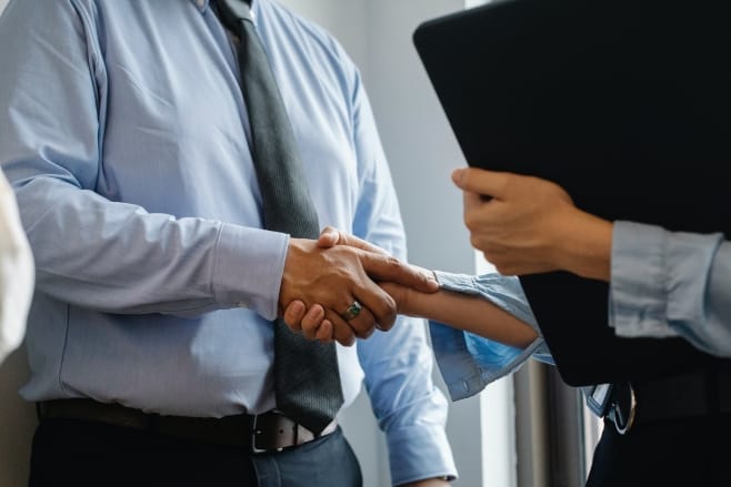 Dos personas formalizan un contrato con un apreton de manos
