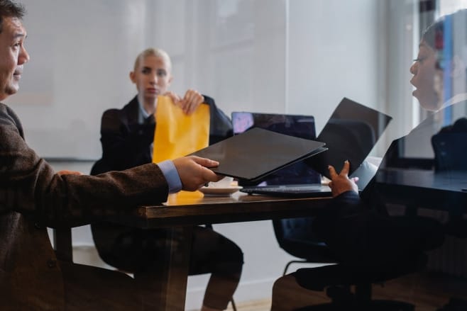 Reunión de tres personas, incluyendo a un mediador, representando la mediación en conciliaciones judiciales y extrajudiciales para alcanzar acuerdos efectivos.