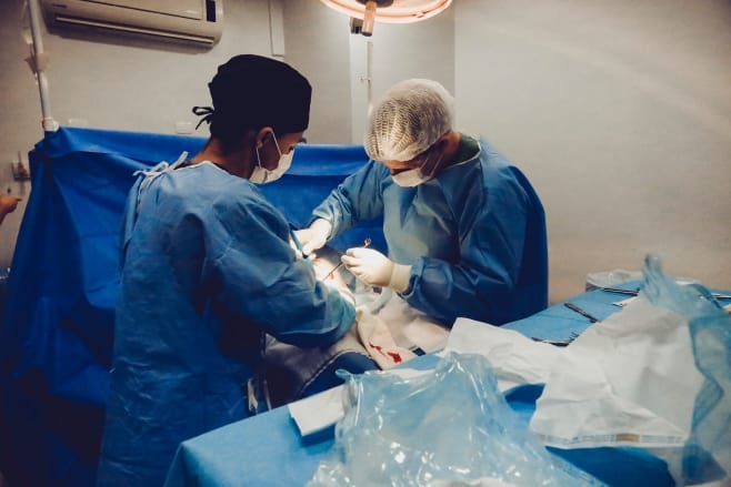 Imagen de dos médicos realizando una cirugía, destacando la necesidad de precisión y atención en entornos médicos para prevenir casos de negligencia médica